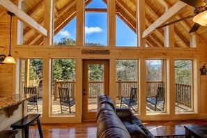 A spacious cabin with a high ceiling, large windows, and a cozy seating area.