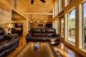 A wooden interior with a leather sofa, a coffee table, and a dining area.