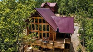 A multi-story log cabin with a metal roof, multiple balconies, and a deck area. - Cabin + FREE Resort Amenities | Pigeon Forge (Pigeon Forge)