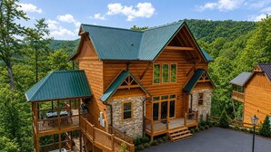 A two-story log cabin with a stone foundation, a covered deck, and a stone fireplace. - Near Dollywood + Resort Amenities Included (Pigeon Forge)