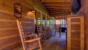 L’intérieur d’un chalet en bois, avec une véranda comprenant des chaises en bois et une pancarte de bienvenue.