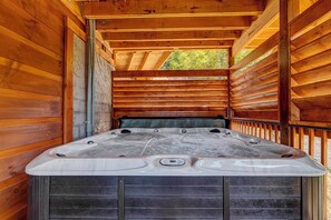 Relax in a hot tub with multiple jets and a control panel, surrounded by a cozy cabin atmosphere.