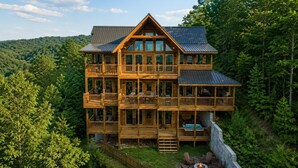 Eine mehrstöckige Holzhütte mit Balkonen, einer Terrasse und einer Feuerstelle.
