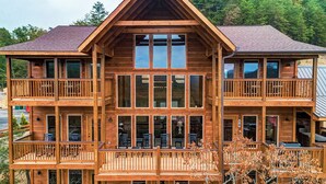 A multi-story wooden cabin with balconies and large windows. - Luxury Cabin w/ All-Inclusive Resort Amenities (Pigeon Forge)