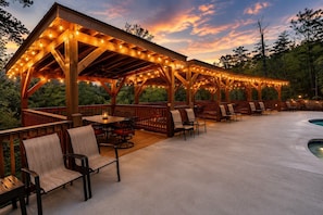 A covered outdoor patio with wooden furniture and string lights.