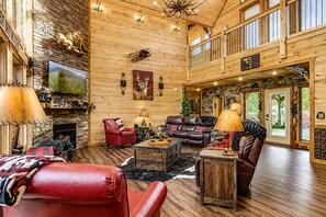 A spacious living room with a fireplace, leather furniture, and a high ceiling.