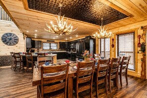 A wooden interior with a dining area, kitchen, and a large clock on the wall.