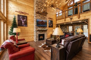 A spacious living area with a fireplace, leather seating, and a high ceiling with wooden beams. - Near Dollywood + Resort Amenities Included (Pigeon Forge)
