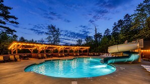 A swimming pool with a slide, lounge chairs, and a covered area with string lights. - Near Dollywood + Resort Amenities Included (Pigeon Forge)