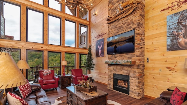A spacious living room with a stone fireplace, leather sofas, and a large TV. - Near Dollywood + Resort Amenities Included (Pigeon Forge)
