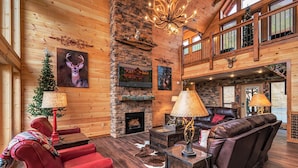 A spacious living room with a fireplace, leather sofas, and a high ceiling with wooden beams. - Near Dollywood + Resort Amenities Included (Pigeon Forge)