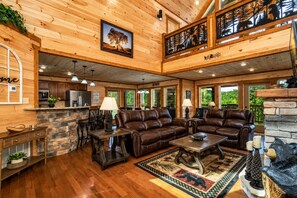 A spacious living area with a fireplace, leather sofas, and a stone accent wall.