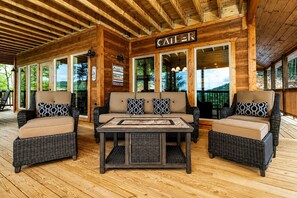 A covered outdoor seating area with wicker furniture, a wooden ceiling, and a sign that reads 'CATER'.