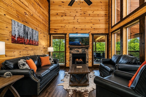 A log cabin interior with a fireplace, leather sofas, and a large painting on the wall.