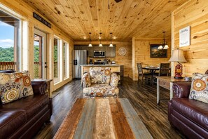 L’intérieur d’une cabine comprenant un canapé, un fauteuil à motifs, une table à manger et un coin cuisine.