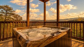 A hot tub on a wooden deck with a view of mountains and trees. - Luxury Cabin w/ All-Inclusive Resort Amenities (Sevierville)