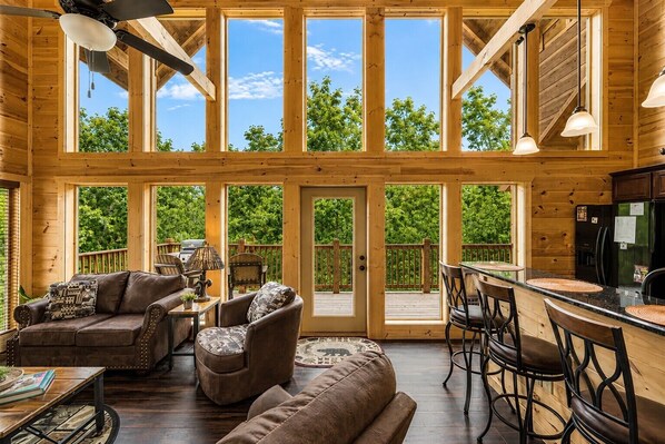 A spacious wooden cabin with large windows, a dining area, and a kitchen.