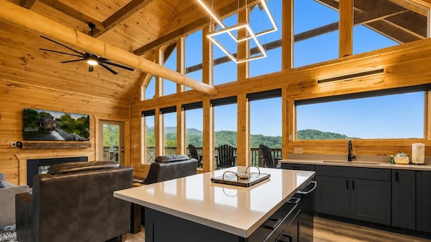 A spacious cabin interior with a large dining area, kitchen, and a scenic mountain view through the windows. - Luxury Cabin w/ All-Inclusive Resort Amenities (Sevierville)