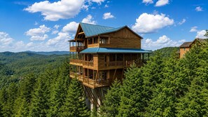 A wooden cabin with a balcony on stilts, surrounded by forest. - Near Dollywood + Resort Amenities Included (Sevierville)