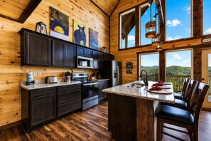 A cabin-style kitchen with dark wood cabinets, a granite countertop, and a large island with bar stools.