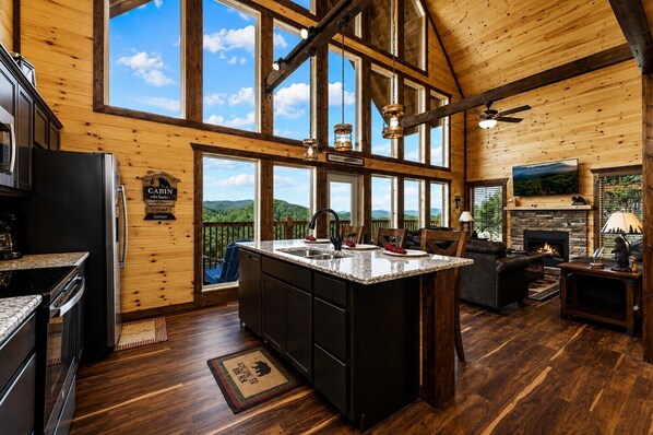 A spacious kitchen with a large island, wooden walls, and a view of the outdoors.