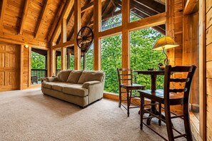 A cozy room with a wooden ceiling, a sofa, a table, and chairs.