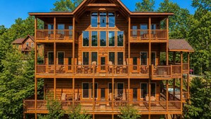 A multi-story wooden cabin with balconies, large windows, and a central entrance. - Luxury Cabin w/ All-Inclusive Resort Amenities (Pigeon Forge)