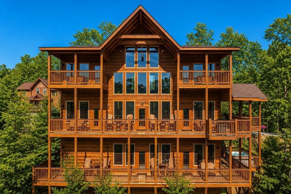 A multi-story wooden cabin with balconies, large windows, and a central entrance.