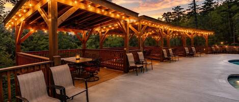 A covered outdoor patio with wooden furniture and string lights.