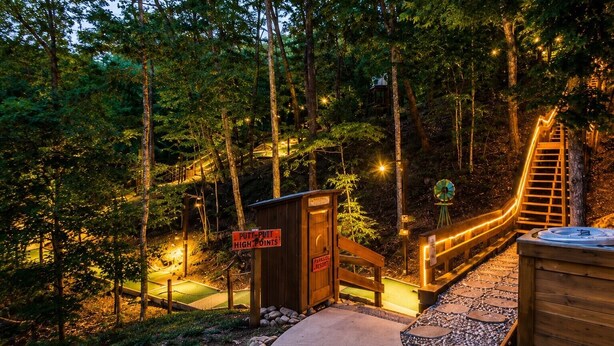 Een houten terras met een jacuzzi, een bordje met 'PUTT-PUTT HIGH POINTS' en een houten constructie met een ladder.
