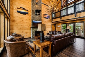 A spacious living room with a fireplace, leather seating, and a stone accent wall.