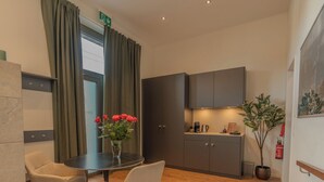 Une pièce moderne comprenant une table ronde, deux chaises, une plante en pot et un coin cuisine avec des placards et un plan de travail.
