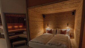 Une chambre confortable avec une tête de lit en bois, un grand lit avec du linge de lit blanc et deux lampes fixées au mur.