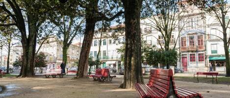Un parc avec des bancs, des arbres et des bâtiments en arrière-plan.