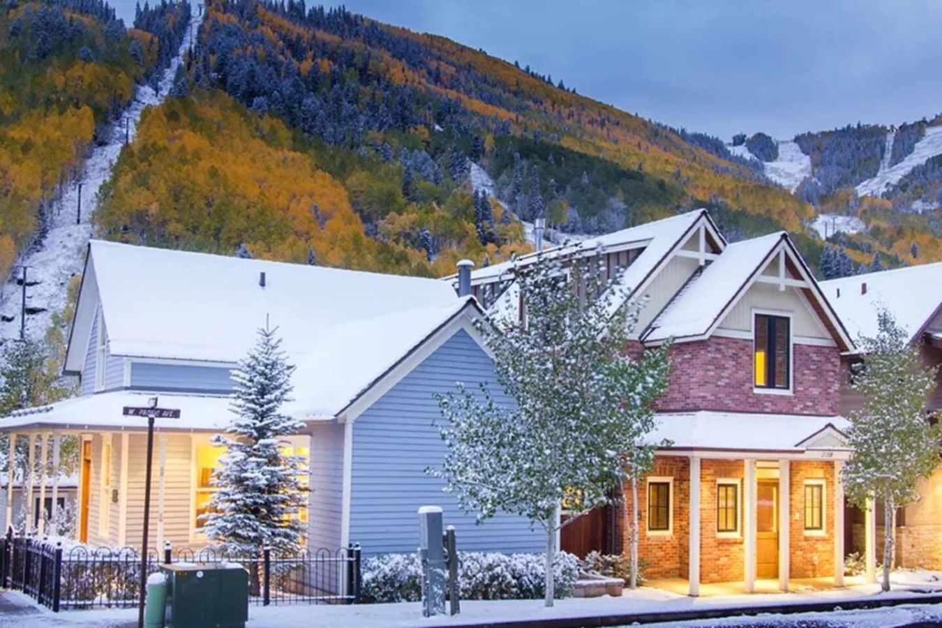 A row of buildings with a mountain backdrop, featuring a mix of architectural styles and a snowy landscape.