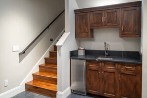 Una cocina con armarios de madera, lavavajillas de acero inoxidable y encimera negra.