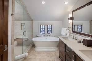 A bathroom with a freestanding bathtub, a glass-enclosed shower, and a vanity with a mirror.