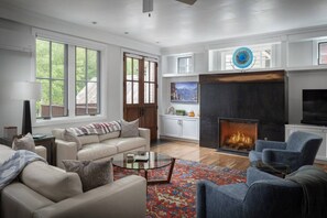A modern living room with a fireplace, leather sofas, a coffee table, and a large window. - South Oak Retreat - convenient luxury by gondola! (Telluride)