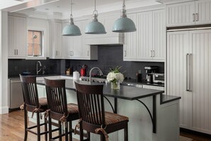 A modern kitchen with white cabinetry, a central island with bar stools, and pendant lighting. - South Oak Retreat - convenient luxury by gondola! (Telluride)