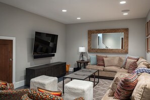 Una sala de estar con televisor de pantalla plana, un sofá, una mesa de centro y una chimenea.