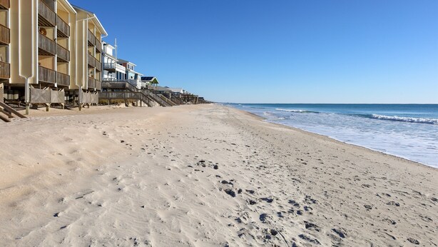 A beachfront hotel with multiple balconies, a sandy beach, and ocean views. - Blue Oar- Beach, Pool, and Sun in Surf City! (Surf City)