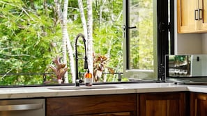 A kitchen with a window, a sink, and wooden cabinets. - Selva Blanca, Jungle Retreat (Playa Hermosa)
