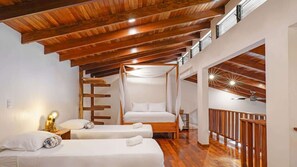A bedroom with two beds, a wooden ceiling, and a balcony. - Selva Blanca, Jungle Retreat (Playa Hermosa)