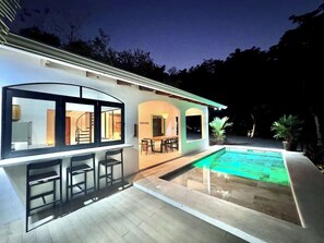A modern house with a swimming pool, bar area, and outdoor seating.