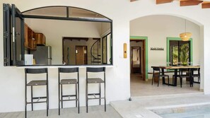 Eine Bar mit Hockern, ein Esstisch mit Stühlen und Blick in die Küche.