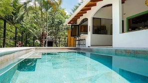 A swimming pool with a clear blue water, surrounded by lush greenery and a modern building with large windows. - Selva Blanca, Jungle Retreat (Playa Hermosa)