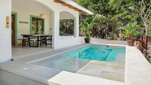 A pool area with a dining setup and a view of the surrounding greenery. - Selva Blanca, Jungle Retreat (Playa Hermosa)