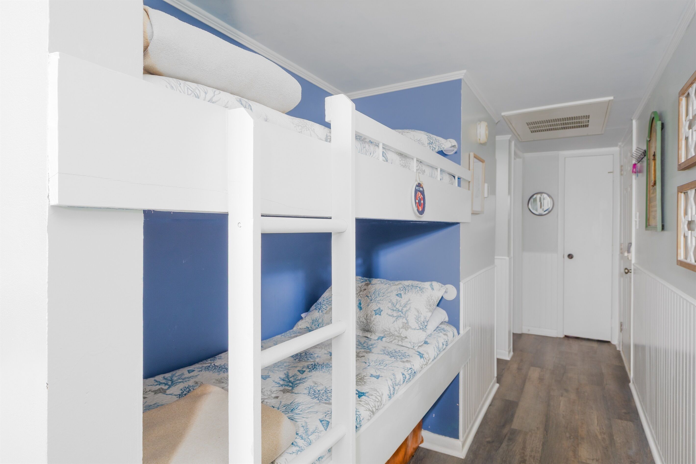 Une chambre avec un lit superposé, un mur bleu et une porte blanche.