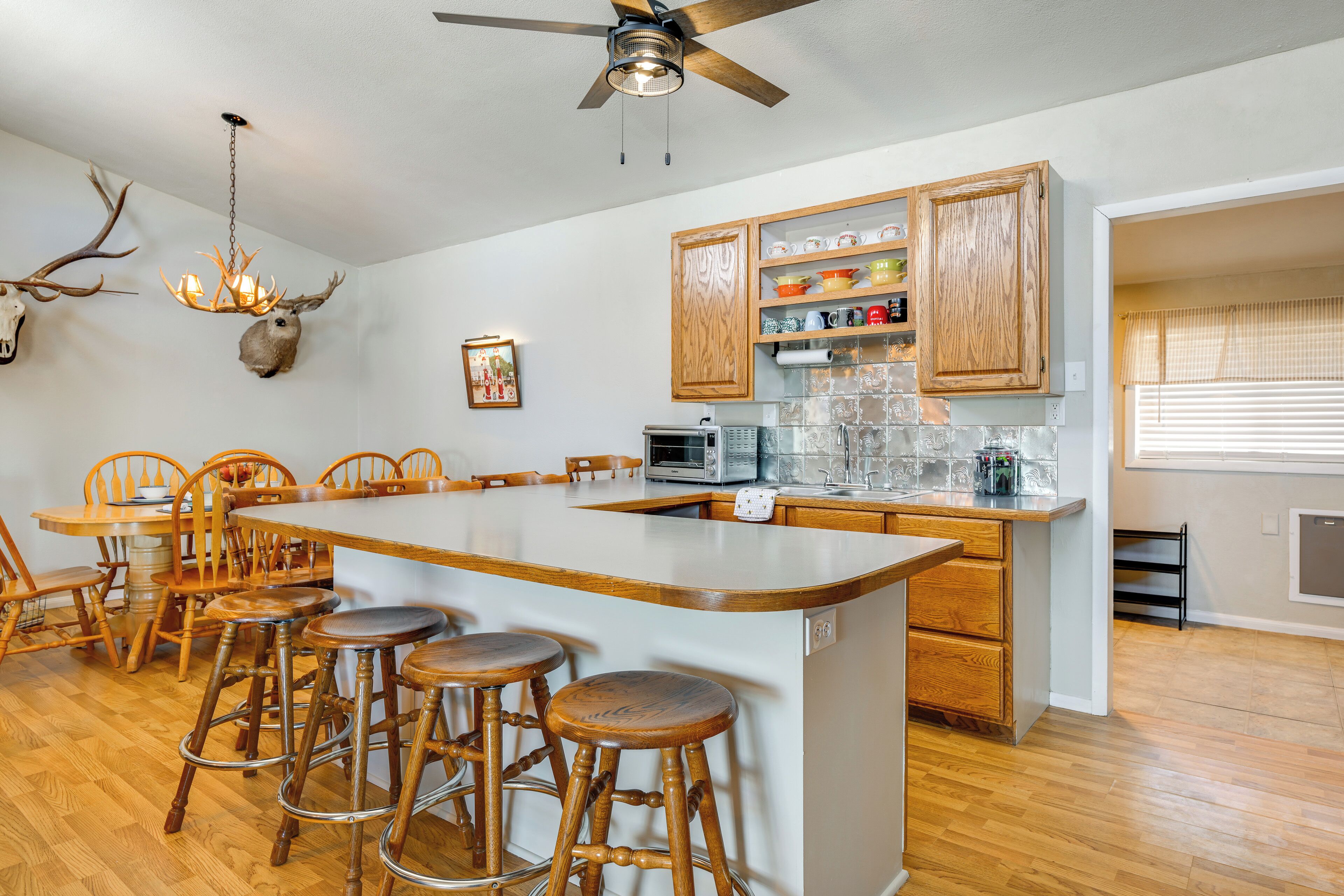 A kitchen with a central island, wooden chairs, and a ceiling fan.
