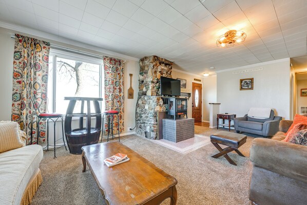 A cozy living room with a stone fireplace, a television, and comfortable seating. - 8 Mi to Hiking: Home w/ Patio in Dtwn Pioche (Pioche)